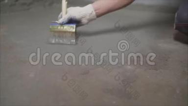 工人用刷子润湿混凝土地板。 用毛刷湿润混凝土地面.. 地板防水准备阶段